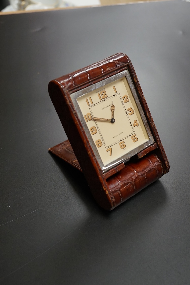 A Finnegan's leather cased travelling timepiece and a base metal Glow Worm pocket watch.